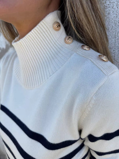 White sweater with black stripes and gold buttons.