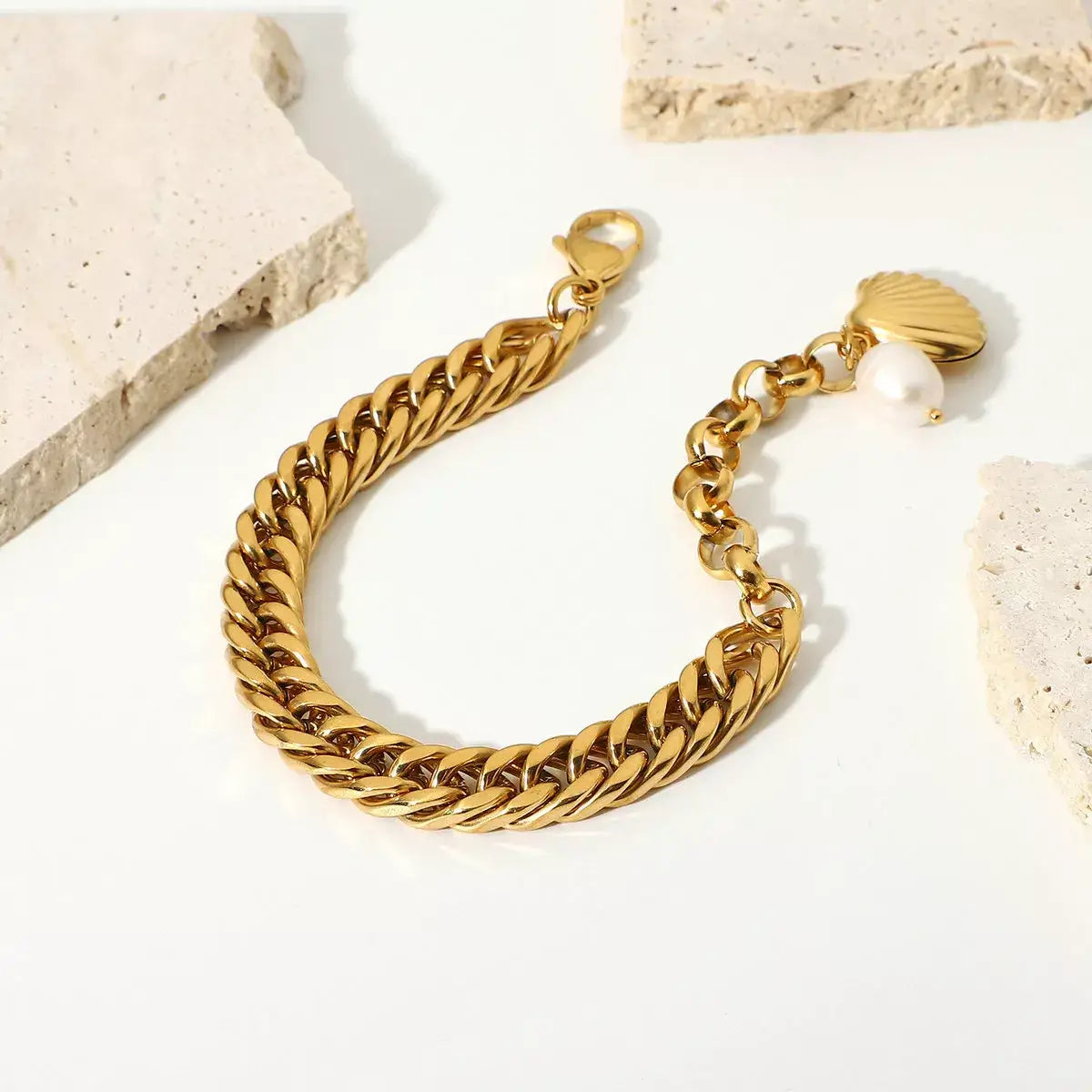 Gold chain bracelet with a pearl charm on a light background