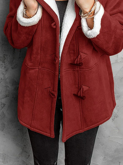 "Person wearing red sherpa toggle coat against concrete wall"