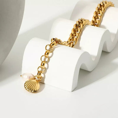 Gold chain bracelet with shell pendants on a white surface