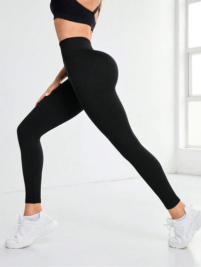 Person wearing black leggings and a black sports bra on a white background