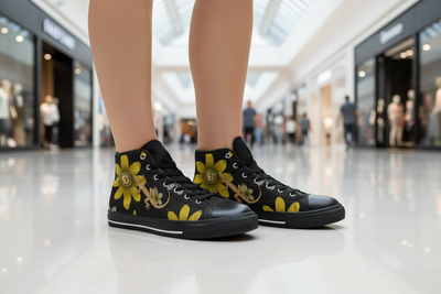 Black high-top sneakers with yellow floral designs worn in a mall setting