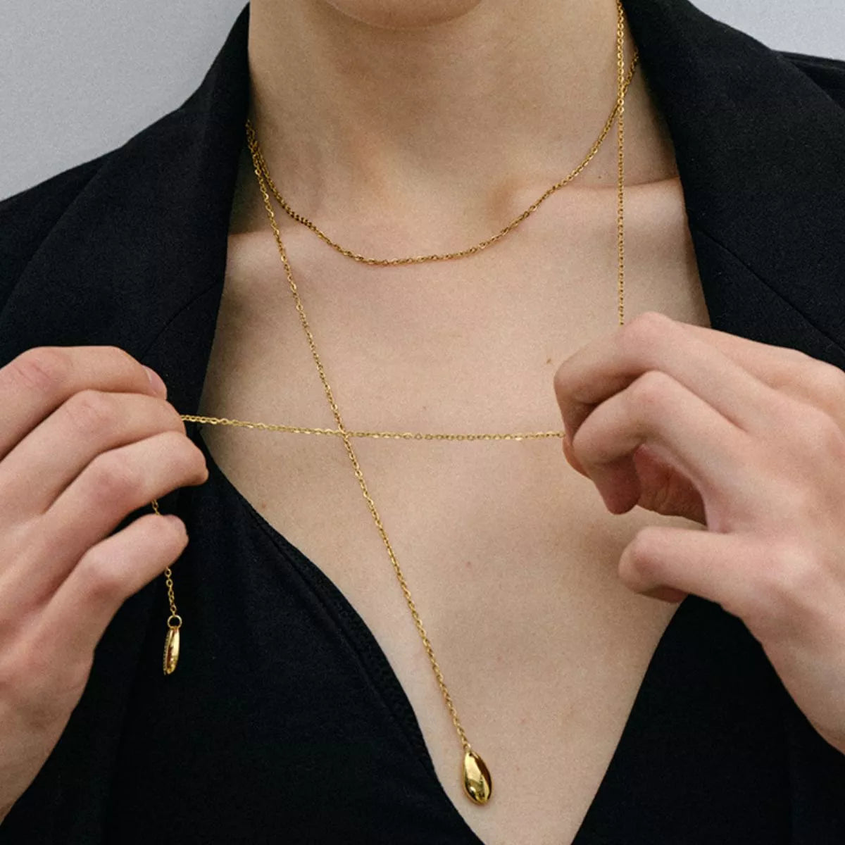 Person wearing a gold body chain with a plain background