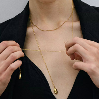 Person wearing a gold body chain with a plain background