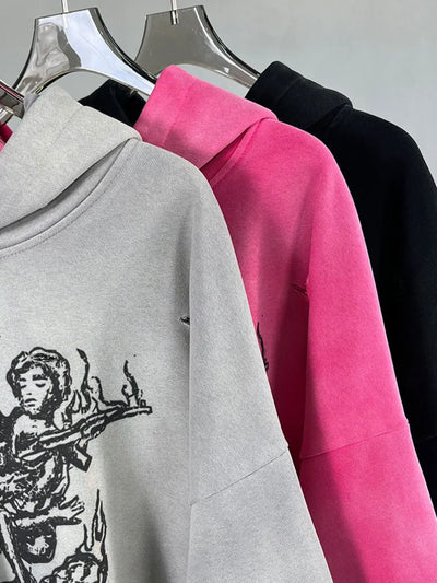 Men's Graphic Long Sleeve Hoodie in grey, pink, and black hanging on display, showcasing artistic design and oversized fit.