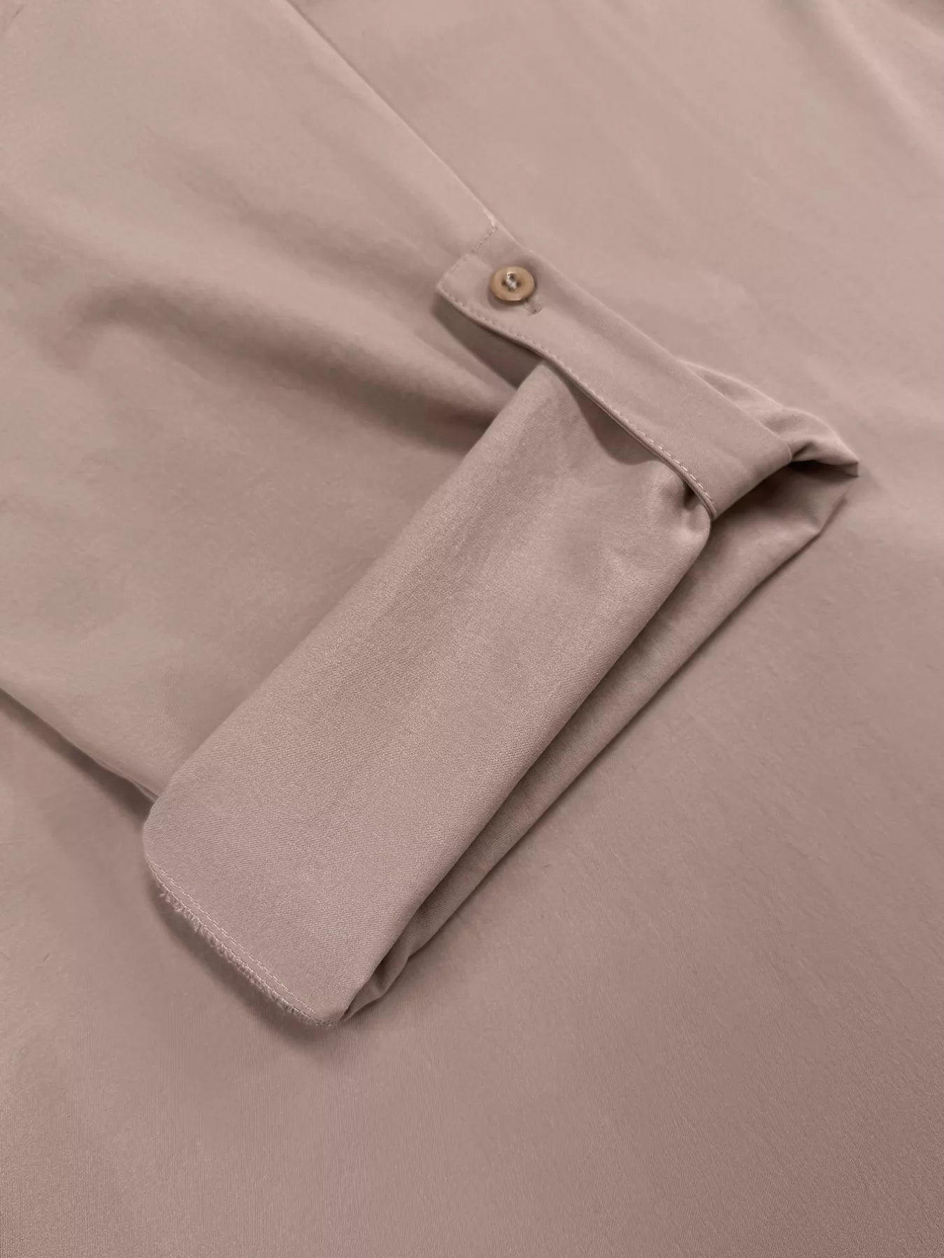 Close-up of a beige shirt with a button on a beige background