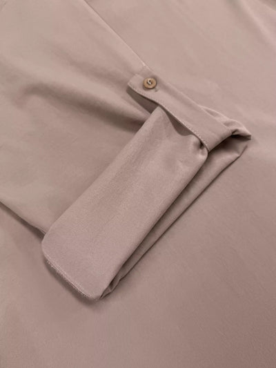 Close-up of a beige shirt with a button on a beige background