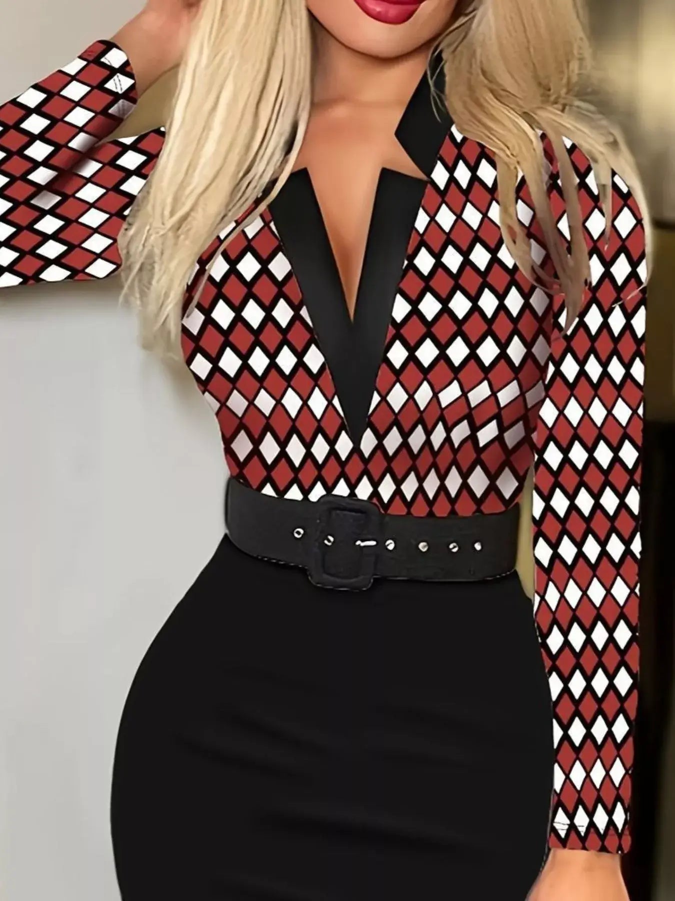 Person wearing a red and black checkered blouse with a black belt against a neutral background