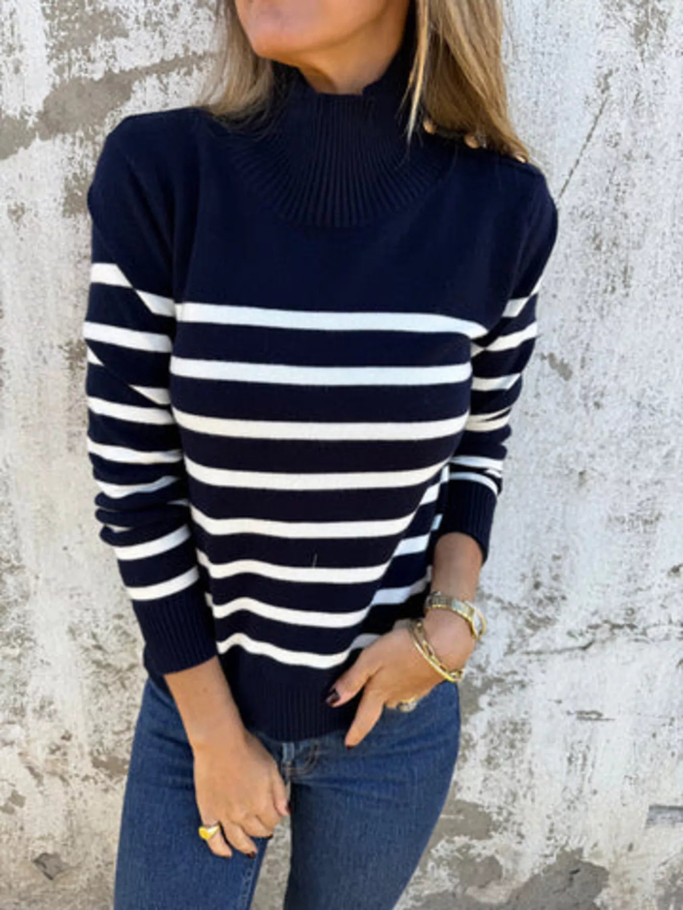 Person wearing a navy and white striped sweater against a textured wall.