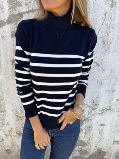Person wearing a navy and white striped sweater against a textured wall.