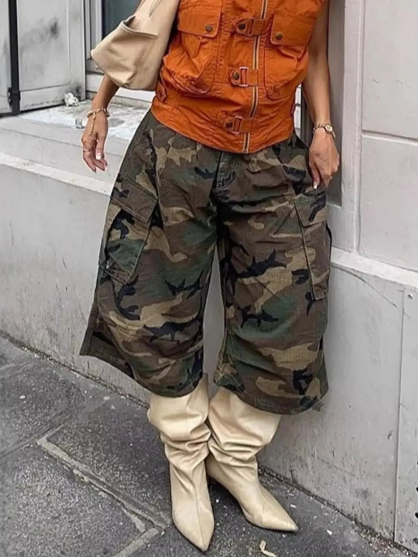 Woman wearing Camouflage Cargo Cropped Pants with pockets, styled with an orange vest and beige boots.