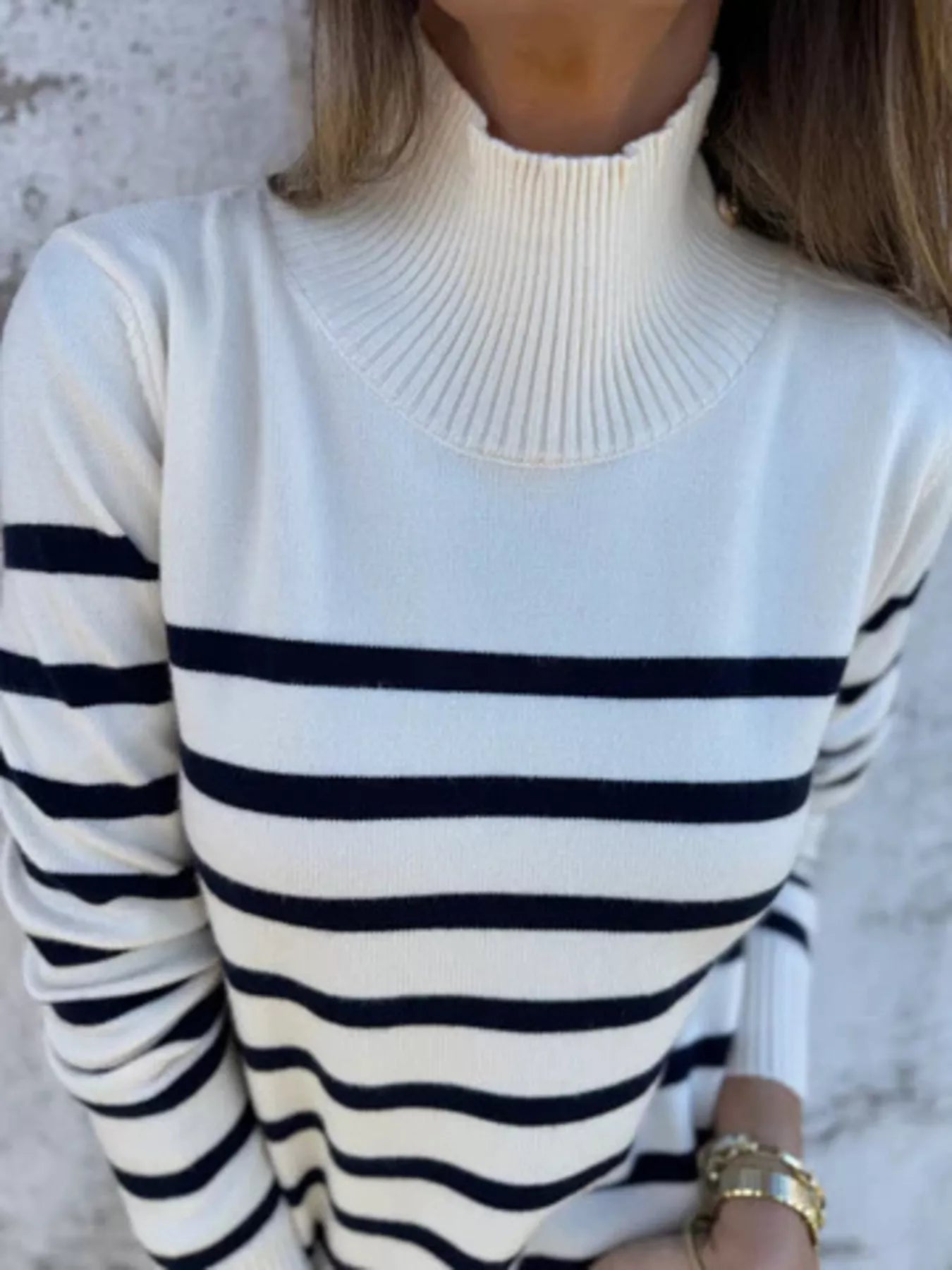 White turtleneck sweater with black horizontal stripes worn by a person.