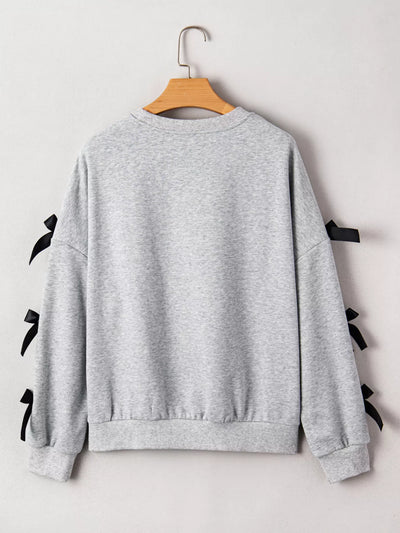 Gray sweatshirt with black ribbons on sleeves and back, hanging on a wooden hanger against a white background.